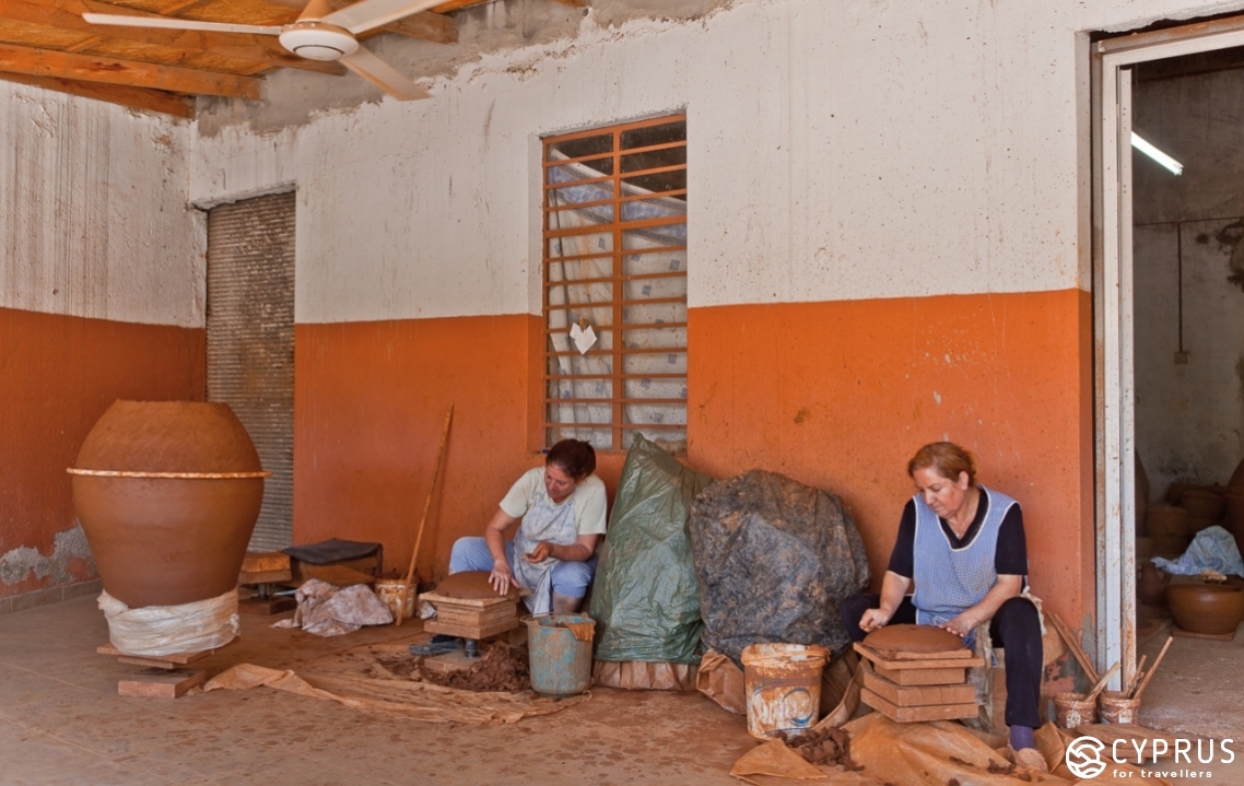  a potter sits working by the entrance to his workshop