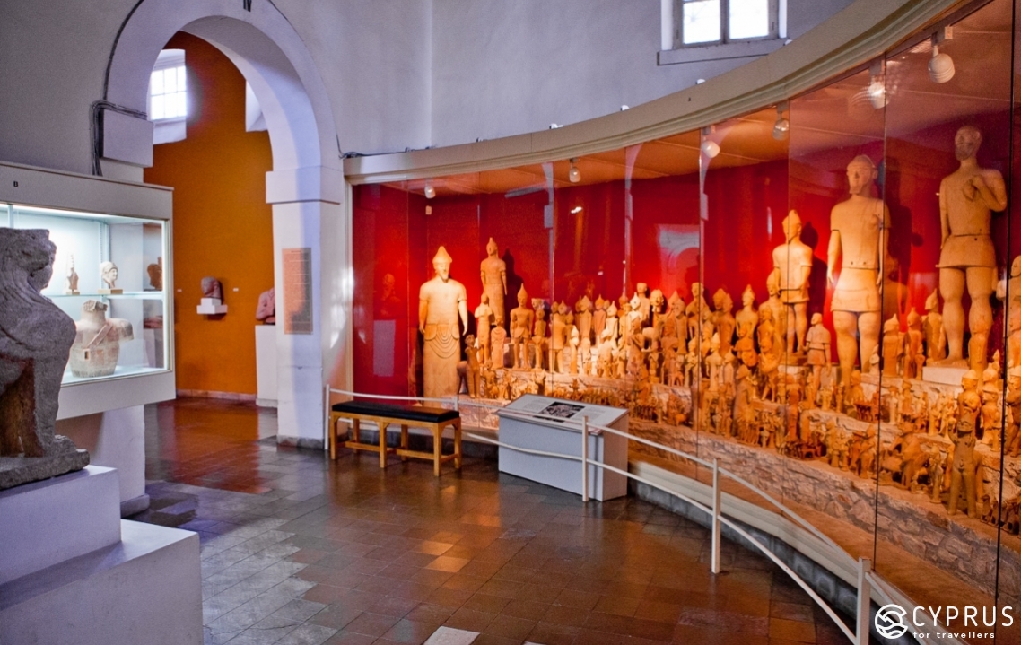Photo of a semi-circular display case with numerous terracotta figures from the Museum of Cyprus
